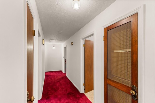 corridor with carpet flooring and a textured ceiling