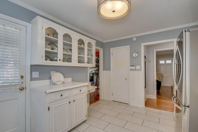 413 Park Dr, Waynesboro, GA 30830 - kitchen with freestanding refrigerator, ornamental molding, light countertops, glass insert cabinets, and white cabinetry