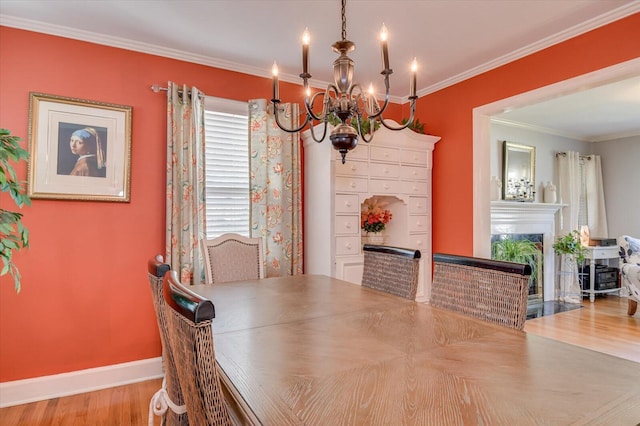 413 Park Dr, Waynesboro, GA 30830 - dining space featuring crown molding, baseboards, a chandelier, a fireplace with flush hearth, and wood finished floors