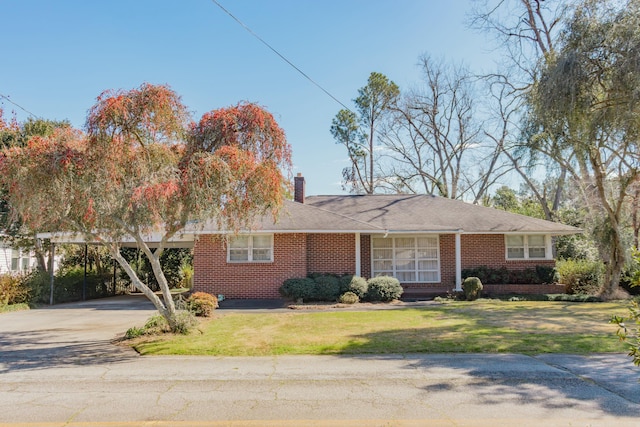 ranch-style home featuring brick siding, a chimney, and a front yard