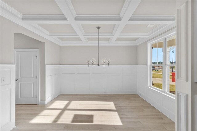 spare room with an inviting chandelier, light wood finished floors, beam ceiling, and coffered ceiling