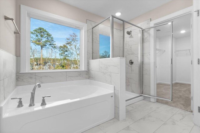 bathroom featuring marble finish floor, a spacious closet, a shower stall, a bath, and recessed lighting