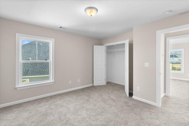 unfurnished bedroom with a closet, light carpet, visible vents, and baseboards