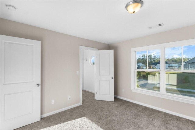 unfurnished bedroom featuring light carpet, baseboards, and visible vents