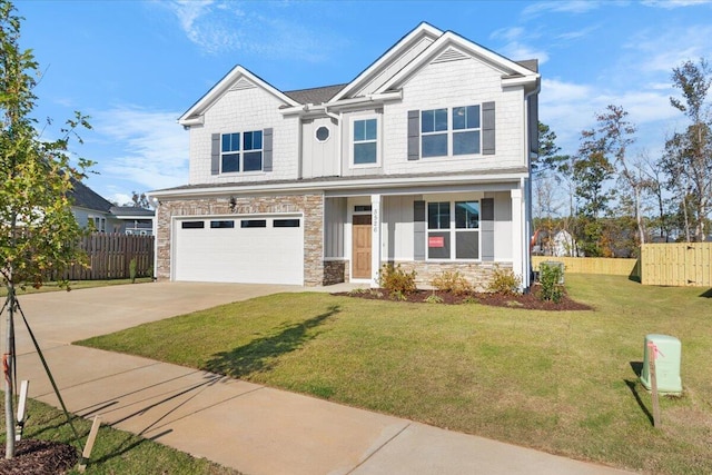 craftsman-style home with concrete driveway, stone siding, an attached garage, fence, and a front lawn