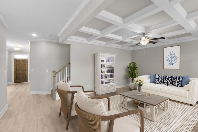 living area featuring light wood-style floors, beam ceiling, coffered ceiling, and stairway