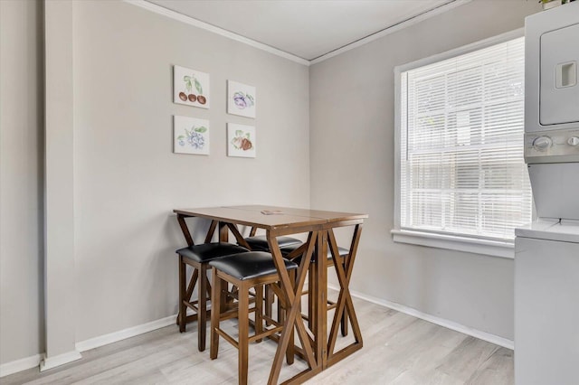 dining space with light hardwood / wood-style floors, stacked washing maching and dryer, and ornamental molding