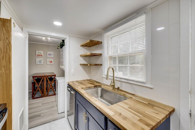 kitchen featuring butcher block countertops, stainless steel dishwasher, ornamental molding, and sink