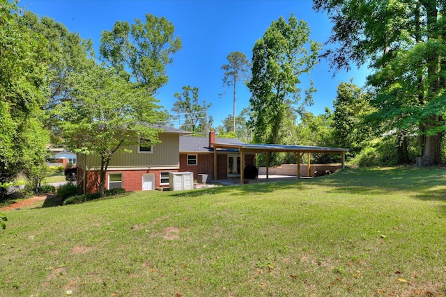 813 Hammond Dr, North Augusta, SC 29841 - back of house featuring brick siding, a lawn, a chimney, an attached carport, and a patio area
