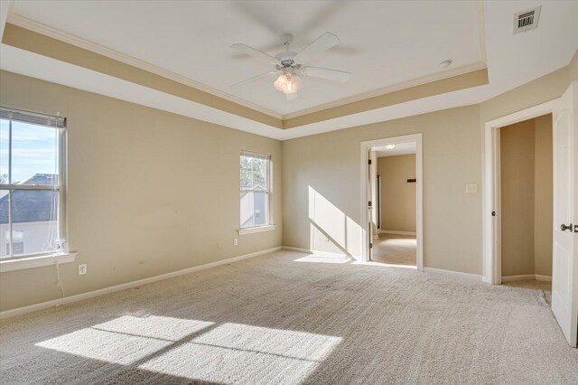 spare room featuring ceiling fan, light colored carpet, crown molding, and a tray ceiling