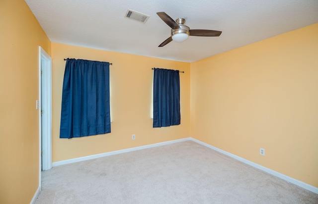 empty room with visible vents, baseboards, a ceiling fan, and carpet flooring