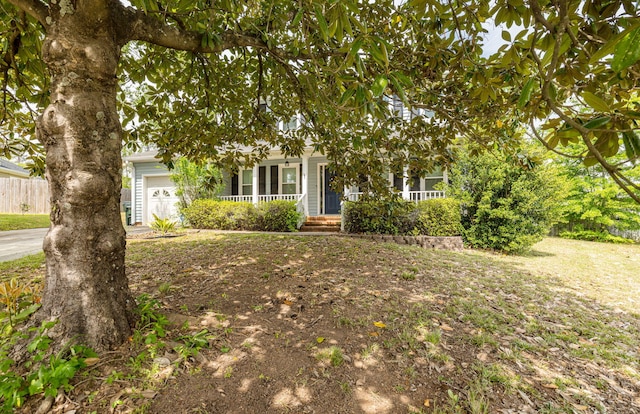 obstructed view of property featuring a porch, fence, and an attached garage
