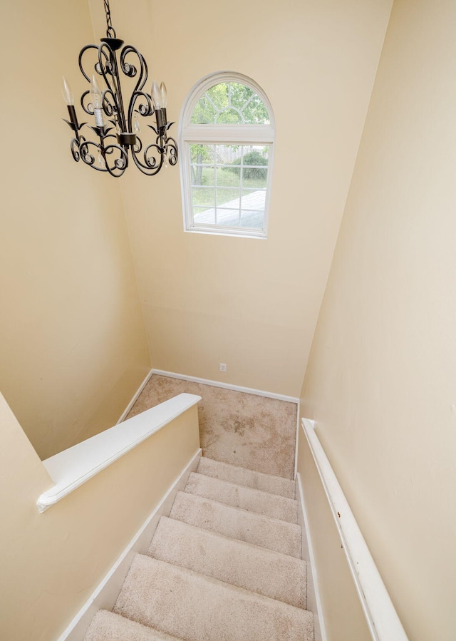 staircase featuring a chandelier and carpet floors