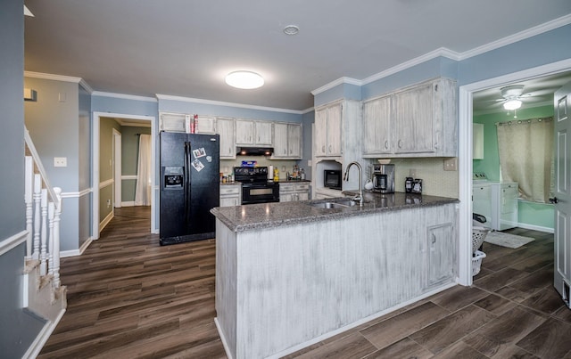 kitchen featuring dark wood-style flooring, a peninsula, washing machine and clothes dryer, black appliances, and a sink