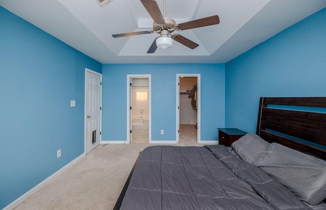 carpeted bedroom with a closet, baseboards, ensuite bathroom, a ceiling fan, and a walk in closet
