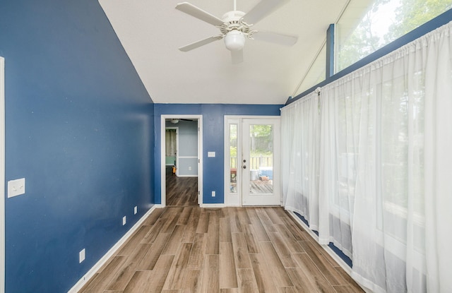 interior space with wood finished floors, ceiling fan, baseboards, and lofted ceiling
