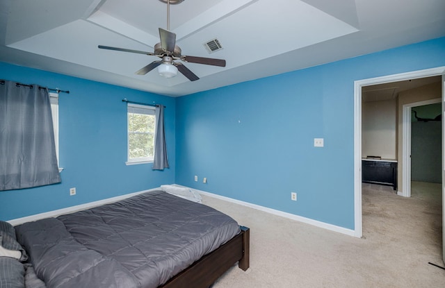 carpeted bedroom with a raised ceiling, baseboards, a ceiling fan, and visible vents