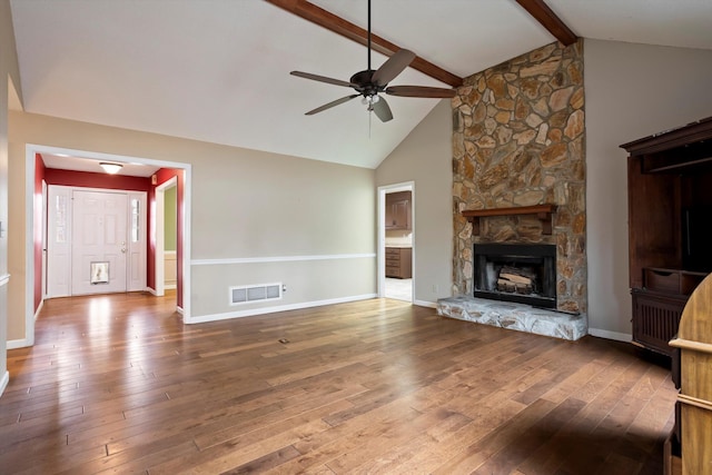 unfurnished living room with ceiling fan, a stone fireplace, beamed ceiling, high vaulted ceiling, and hardwood / wood-style flooring