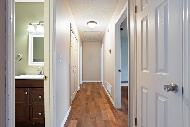 hall featuring a textured ceiling, light hardwood / wood-style floors, and sink