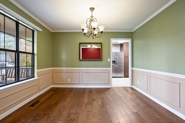 unfurnished dining area featuring crown molding, a chandelier, and dark hardwood / wood-style floors