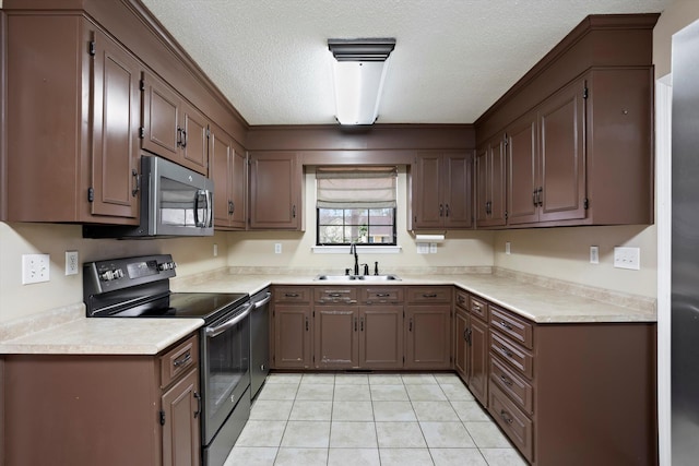 kitchen featuring sink, light tile patterned floors, a textured ceiling, and appliances with stainless steel finishes