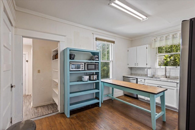 kitchen featuring stainless steel appliances, a sink, dark wood-style flooring, light countertops, and white cabinets