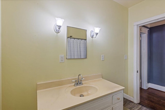 bathroom with wood finished floors, baseboards, and vanity