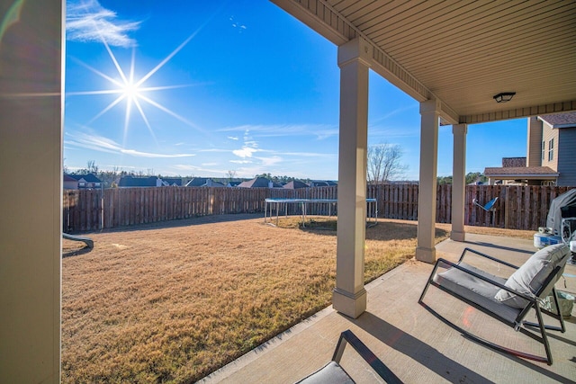 view of yard with a trampoline and a patio