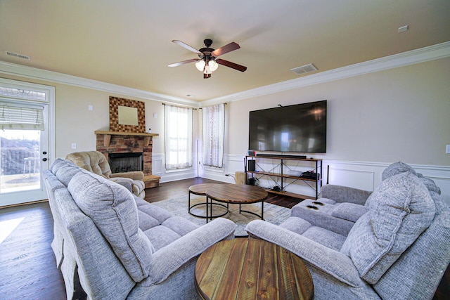 living room featuring a fireplace, ceiling fan, crown molding, and wood-type flooring