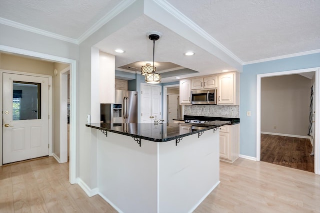 4610 Mulberry Creek Dr, Evans, GA 30809 - kitchen featuring appliances with stainless steel finishes, a breakfast bar area, light wood-type flooring, a peninsula, and a textured ceiling