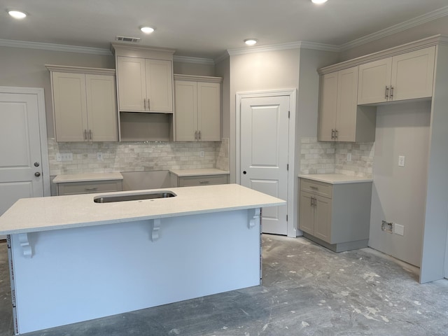 kitchen featuring visible vents, a kitchen bar, gray cabinetry, ornamental molding, and a center island