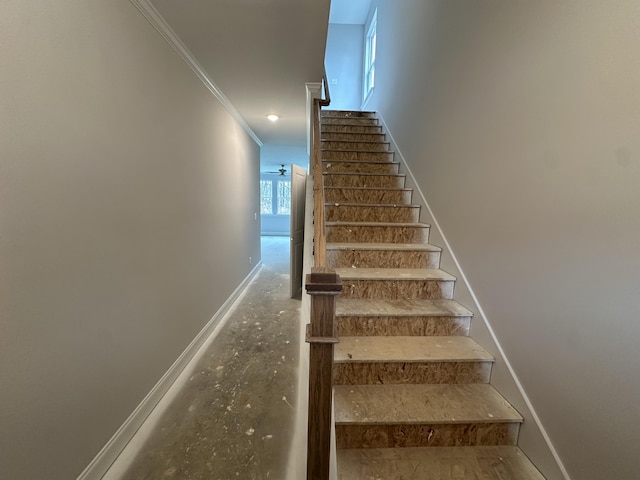 stairway featuring baseboards, a ceiling fan, and crown molding