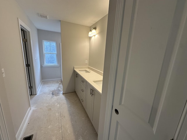 bathroom with visible vents, a sink, baseboards, and double vanity