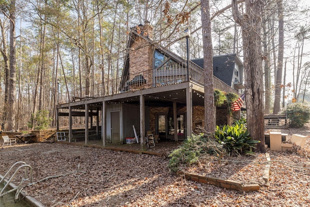 back of property with a shingled roof and a wooden deck