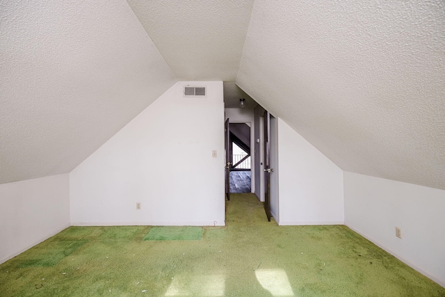 additional living space featuring visible vents, light carpet, vaulted ceiling, a textured ceiling, and baseboards