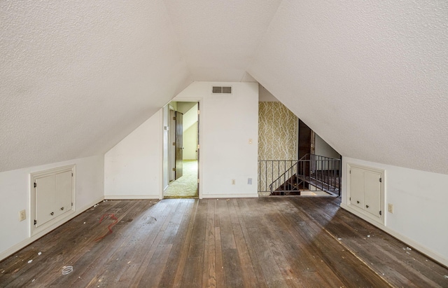 bonus room with a textured ceiling, dark wood-type flooring, and visible vents