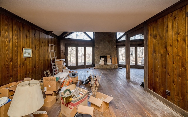 unfurnished living room with wood walls, vaulted ceiling, wood finished floors, and french doors