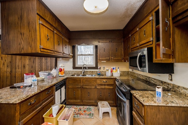 kitchen with light tile patterned floors, appliances with stainless steel finishes, light stone counters, and a sink