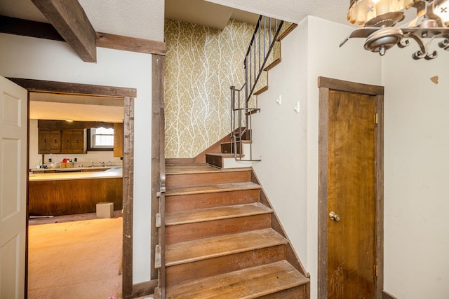 staircase with beamed ceiling and a textured ceiling