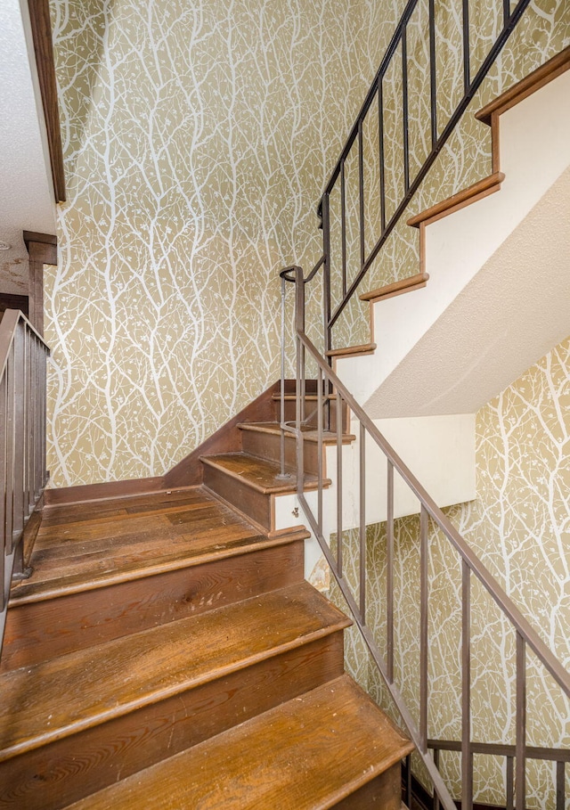 stairway featuring wallpapered walls