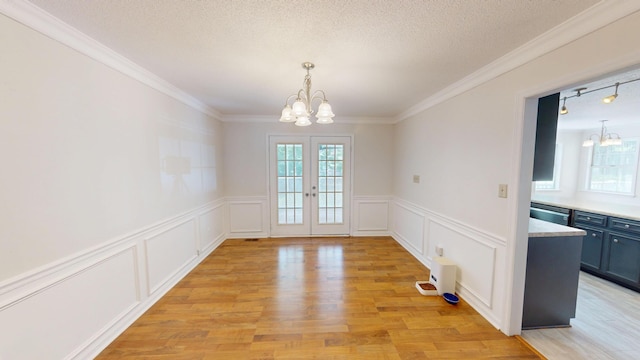 3904 Loblolly Trl, Martinez, GA 30907 - unfurnished dining area with a chandelier, french doors, a decorative wall, light wood finished floors, and crown molding