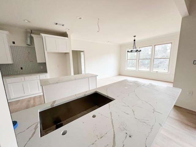 191 Devonshire Dr, Aiken, SC 29803 - kitchen with tasteful backsplash, light stone countertops, ornamental molding, white cabinets, and a chandelier