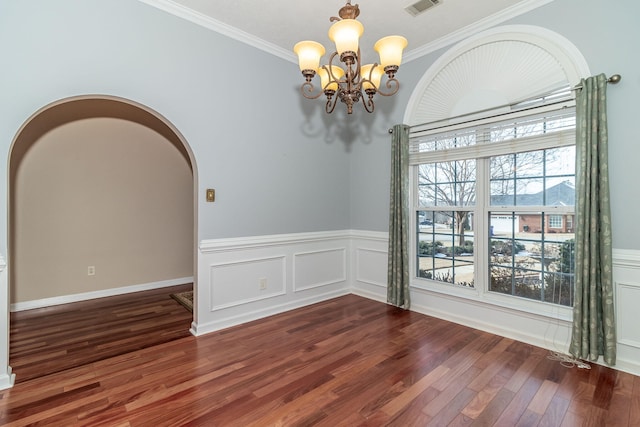 spare room with an inviting chandelier, crown molding, and dark hardwood / wood-style floors