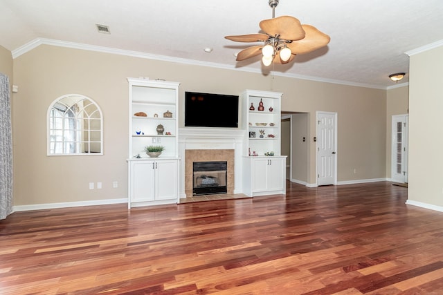 unfurnished living room with hardwood / wood-style flooring, crown molding, a tiled fireplace, and built in features