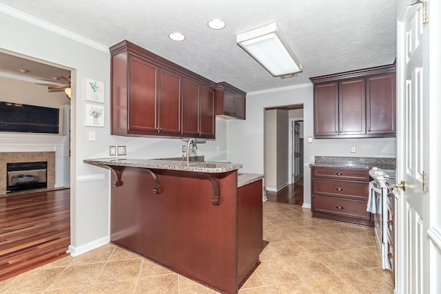 kitchen featuring crown molding, a kitchen breakfast bar, stainless steel range with gas stovetop, and a textured ceiling