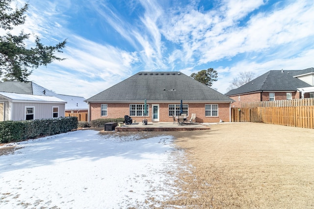 snow covered back of property featuring a patio