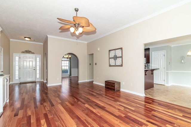 interior space with ceiling fan with notable chandelier, dark wood-type flooring, and ornamental molding