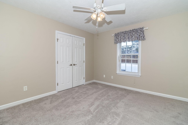 unfurnished bedroom with ceiling fan, light colored carpet, and a closet