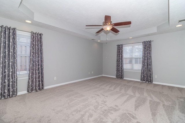 carpeted empty room featuring ceiling fan and a tray ceiling