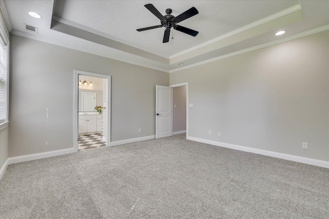 unfurnished bedroom featuring a tray ceiling, light colored carpet, ornamental molding, visible vents, and baseboards